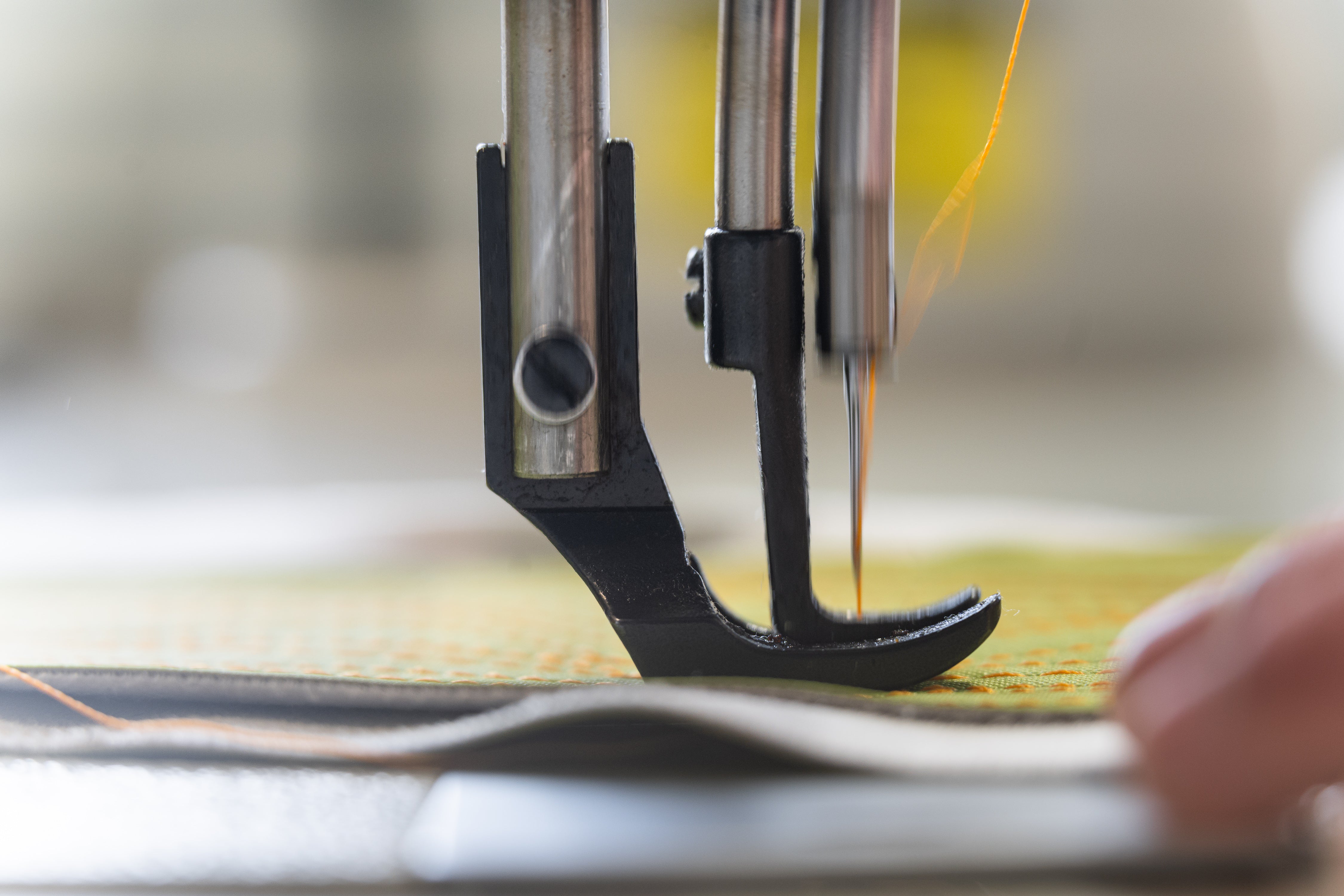 Close-up of a sewing machine needle in action with a blurred background