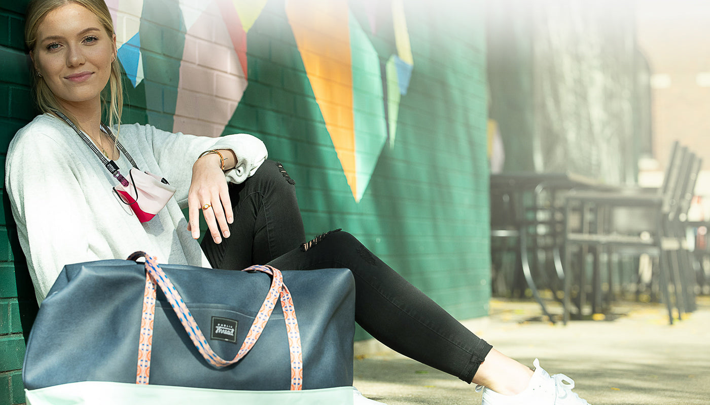 Women sitting on sidewalk with public thread bag